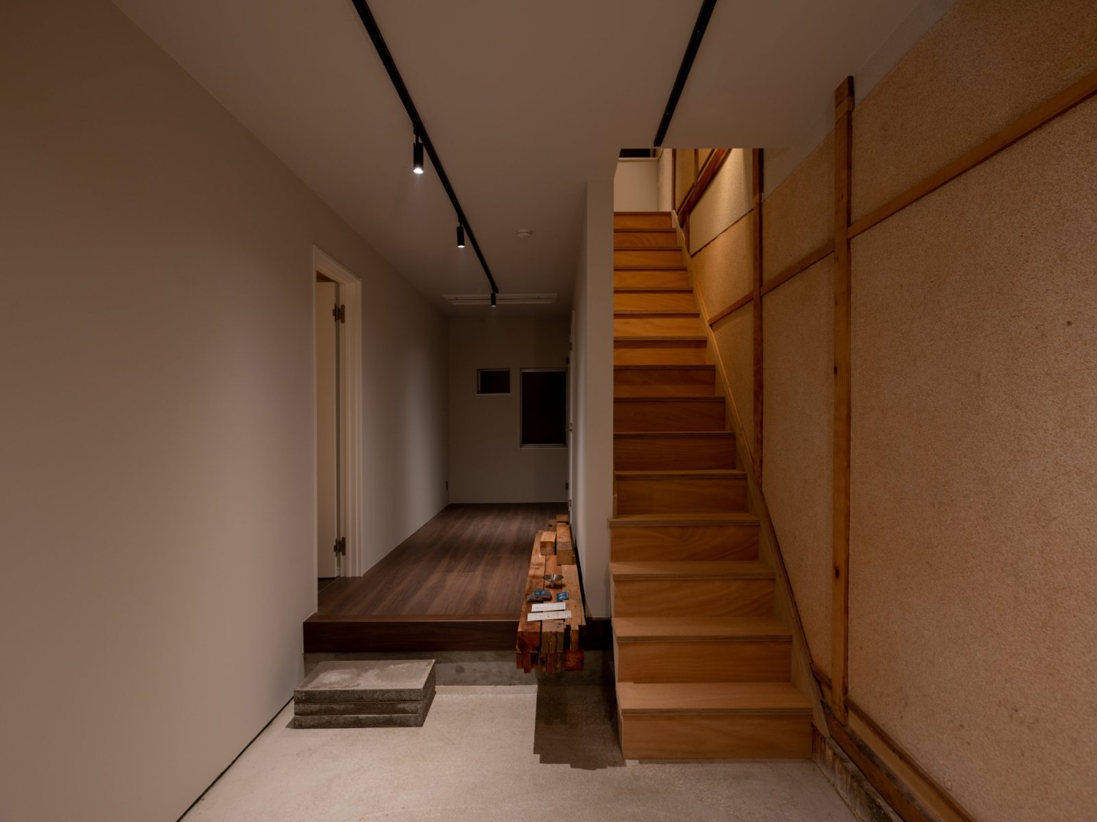 The ground-floor gallery space: concrete floor, track lighting, a raised timber floor and the original stair
